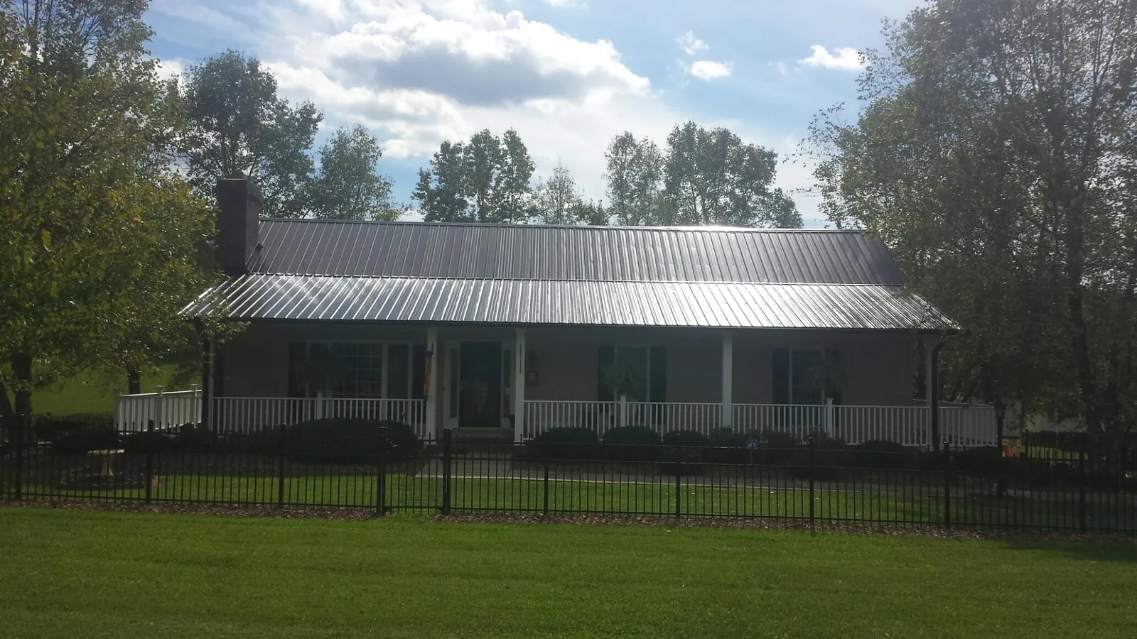 Gray metal roof on a brick ranch with a full width front porch — Gutter Guard Installation work by our crew in Monument