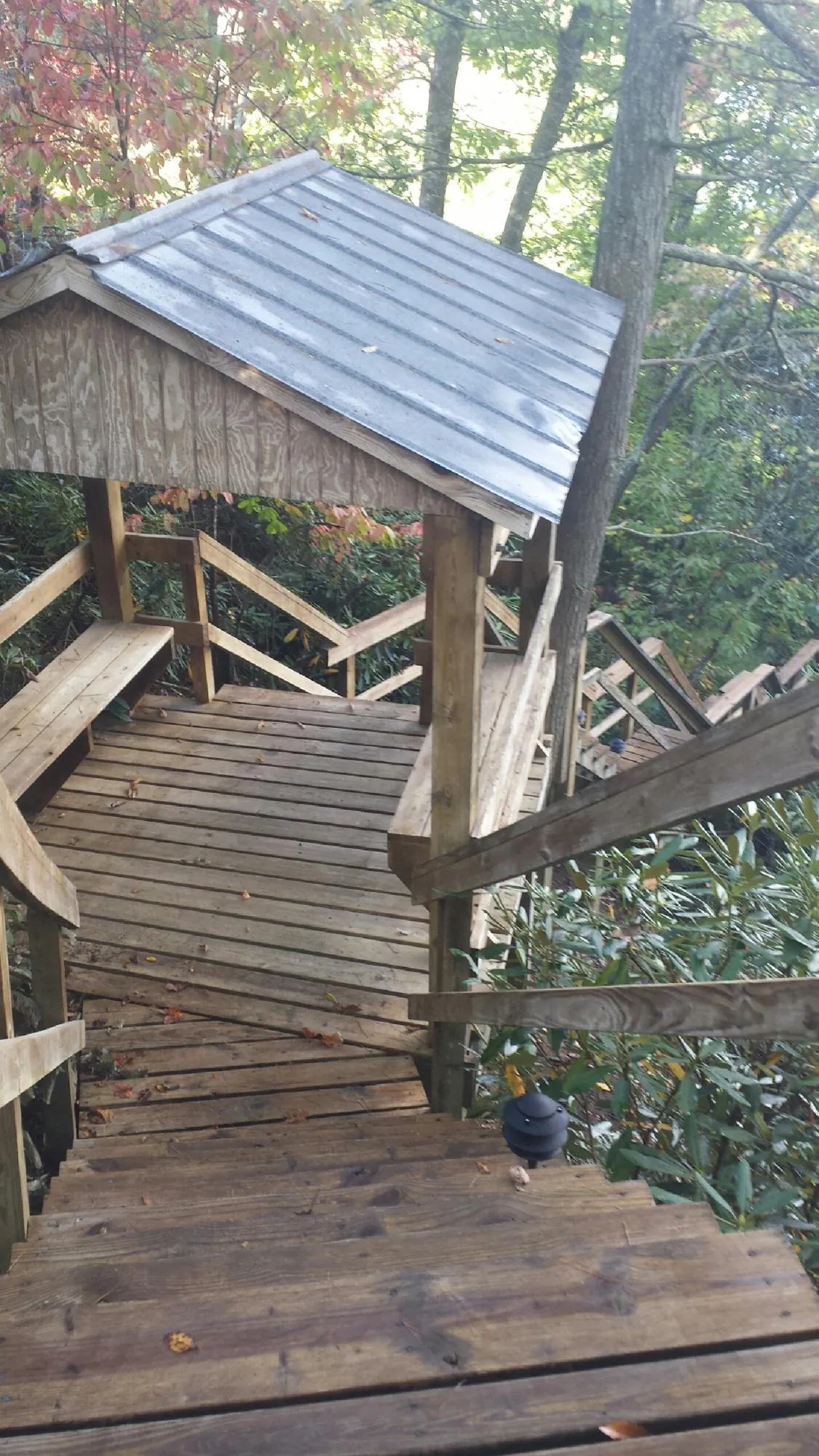 Metal roofed shelter over wooden steps on a wooded walkway — Skylight Repair & Installation work by our crew in Monument
