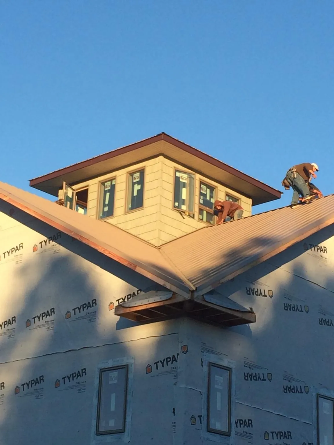 Roofers working around a rooftop cupola on a new metal roof at sunset — Roof Waterproofing in Monument by Roofing Brothers